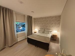 a bedroom with a bed with two lamps and a window at Osterøy Minihotell in Lonevåg