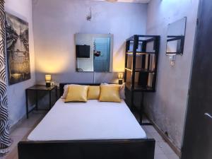 ein Bett mit gelben Kissen in einem Zimmer in der Unterkunft RÉSIDENCE PRIVÉE 1 Chambre avec Salon, Cuisine Équipée, Climatisation, Wifi et Cour Individuelle in Ouagadougou