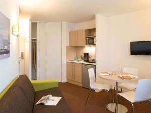 a living room with a couch and a table and a kitchen at Aparthotel Adagio Access Le Havre Les Docks in Le Havre +29 photos