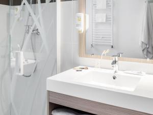 a bathroom with a white sink and a shower at Aparthotel Adagio Access Paris Clichy in Clichy