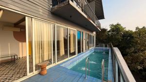 a house with a swimming pool next to a building at Hillora Coastal Resort in Arpora