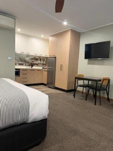 a room with a bed and a table and a kitchen at Barooga River Gums Motor Inn in Barooga