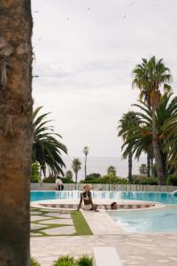 a person sitting in a chair by a swimming pool at President Hotel in Cape Town