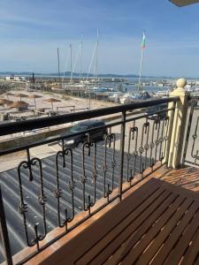 a wooden bench on a balcony with a marina at Студиа При Американеца in Pomorie