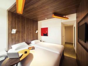 a bedroom with a bed and a desk with a laptop at ibis Styles Niort Poitou Charentes in Vouillé