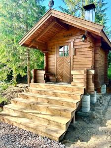 a log cabin with a staircase leading up to the door at Maatilamajoitusta marjatilalla in Sjundeå