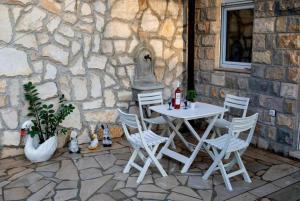 a white table and chairs in front of a stone wall at Apartmani Katarina in Donje Čičevo