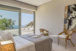 a bedroom with a bed and a large window at Aetos Cave Villa With Sunset in Mylopotas +23 photos