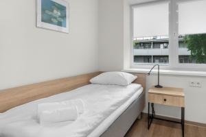a white bedroom with a bed and a window at K4 Jonava Rooms in Jonava