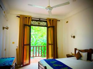 a bedroom with a bed and a window with a balcony at Raniya Villa in Bentota