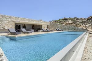 a swimming pool with blue water in front of a house at Aetos Cave Villa With Sunset in Mylopotas