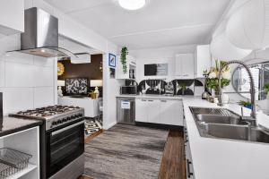 a white kitchen with a sink and a stove at Eleda House - Retro Hidden Gem in Cessnock