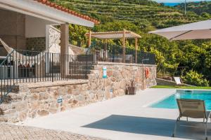 a villa with a swimming pool and a patio with an umbrella at Casa da Alufinha in São João da Fontoura