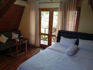 a bedroom with a bed and a table and a window at Agora Home in Wonosobo