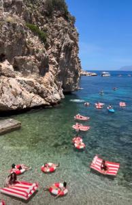 a group of people in the water near a cliff at LE SORELLE Sea front -villa whit private pool in Scopello