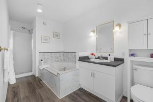 a white bathroom with a tub and a sink at KnoxPeace BnB in Kelowna