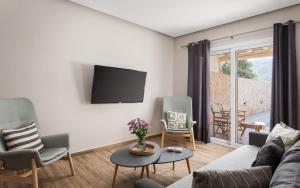 a living room with a couch and chairs and a tv at Olive Tree House in Anavyssos