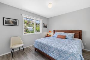 a bedroom with a bed and a chair and a window at KnoxPeace BnB in Kelowna