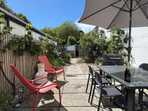 a patio with red chairs and a table with an umbrella at Pilots Lodge by Deal Castle with free parking in Deal