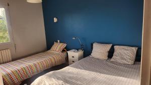 a bedroom with two beds and a blue wall at Maison grande terrasse Poligny in Poligny