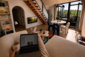a person holding a cup of coffee in a living room with a laptop at Maisonette Wohnung WALDLOFT in Mehlmeisel