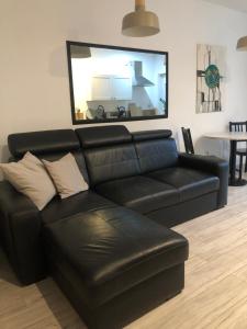a black leather couch in a living room with a large mirror at Apartament Cozy Studio in Żagań