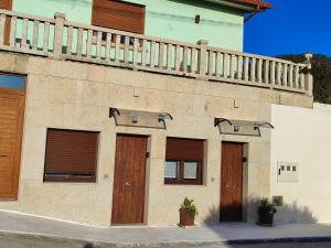 a building with wooden doors and a balcony at Magariños Apartamentos in Oia
