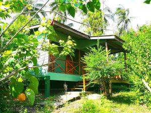 a green house with a porch in a garden at Tampat do Aman in Kudat