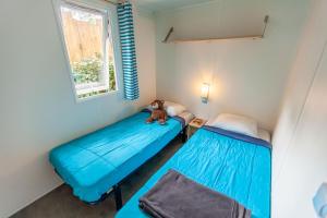 a room with two beds and a teddy bear sitting on the bed at Camping JOBEL in Tarnos