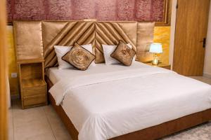 a bedroom with a large white bed with pillows at Airport Side Hotel in Accra