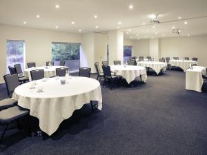 a room with tables and chairs with white table cloths at Mercure North Melbourne in Melbourne +52 photos