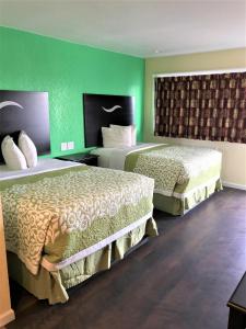 two beds in a hotel room with green walls at Budget Inn in Sedalia