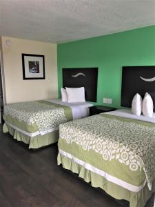 two beds in a hotel room with green walls at Budget Inn in Sedalia