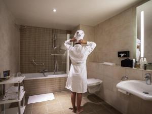 a woman in a bathroom with a towel on her head at Novotel Brussels Centre Midi in Brussels