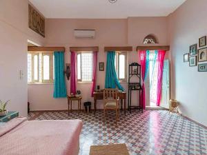 a bedroom with a bed and a table and windows at DanCenter Kolpol by CheckIn Udaipur in Udaipur