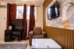 a living room with a chair and a tv on a wall at Airport Side Hotel in Accra +18 photos