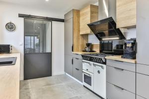 a kitchen with white appliances and wooden cabinets at Villa Boréal with spa in the heart of St Gilles in Saint-Gilles-Croix-de-Vie +11 photos