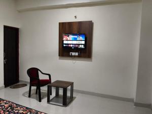 a room with a chair and a tv on a wall at NestIN hotels in Lucknow