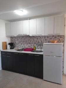 a kitchen with white cabinets and a white refrigerator at Apartmani Goga in Pirovac
