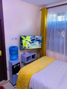 a bedroom with a bed and a flat screen tv at The Crown Stay in Machakos