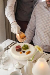 a person pouring food onto a plate on a table at Wanda Luxury Boutique Hotel - tylko dla dorosłych in Szczawnica