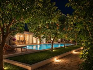 ein Pool bei Nacht mit Bäumen und Lichtern in der Unterkunft Villa Anthousa luxury villas and suites in Anthoúsa