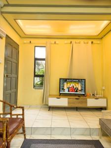 a living room with a tv on a yellow wall at Triple A Kundasang in Ranau