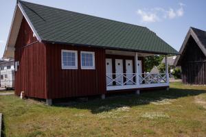 a red house with a gambrel roof at Jahta Engures ostā in Engure