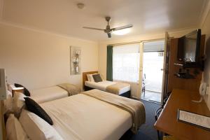 a hotel room with two beds and a television at David Motor Inn in Rockhampton