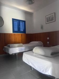 a room with three beds and two blue windows at Montaña Las Tortolas in San Bartolomé