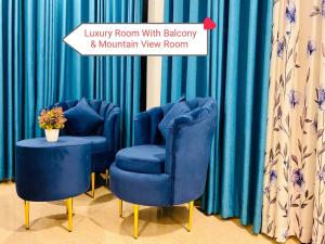 two chairs and a table in a room with blue curtains at Rock Face Palace in Ella