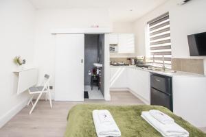 a white kitchen with white cabinets and a sink and a bed at The Belmont Suits in Liverpool