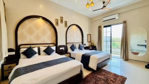 a bedroom with two beds and a large window at Hotel Omkareshwar Jyotirling Inn in Godarpura