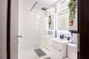 a white bathroom with a shower and a toilet at Deda Studio w. Smart TV · AC · washing machine in Bucharest